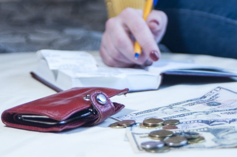 business woman making notes in notepad banknotes dollars pen accounting savings income inter 1024x679